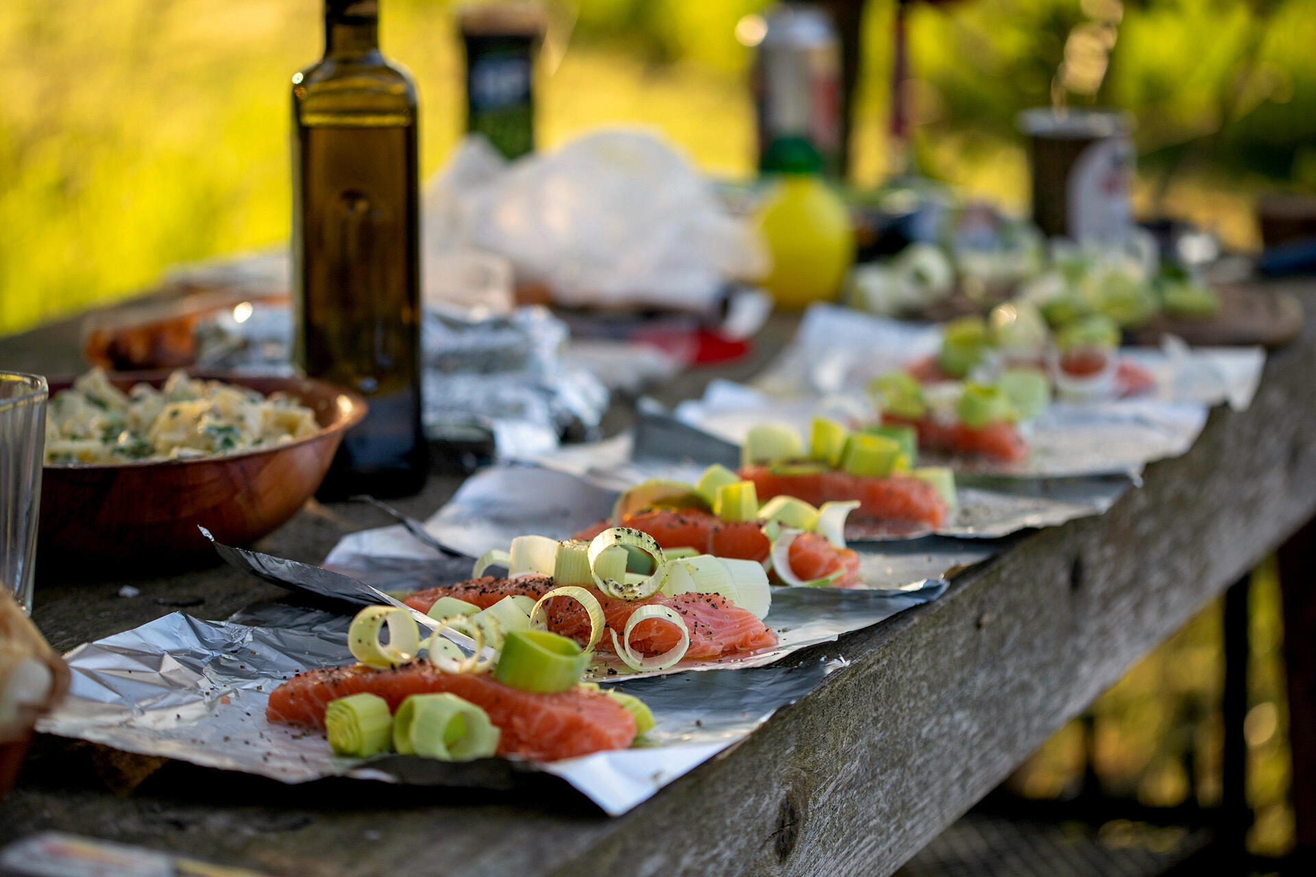 Outdoor table set with fresh salmon, leeks and shared dishes prepared for cooking, reflecting Terra Noma’s approach to designing meaningful, slow family travel centred around connection, food and shared rhythm.