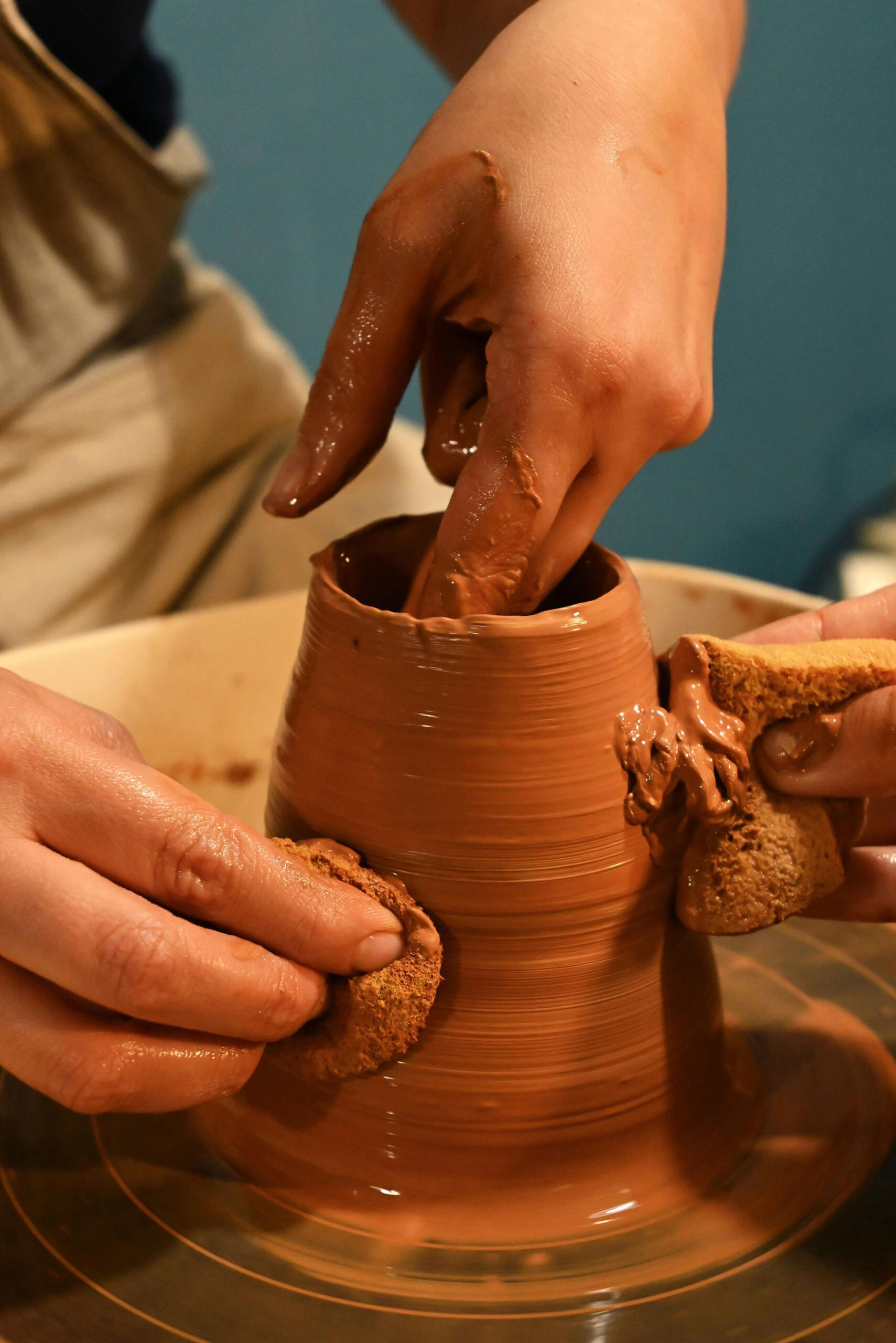 Close-up of clay-covered hands shaping a vessel on a pottery wheel, capturing a tactile moment from a hands-on workshop experience designed by Terra Noma as part of a quiet, creative weekend retreat.